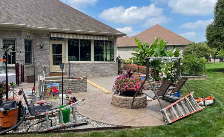 Backyard patio with firepit, ongoing construction of the roofed pergola